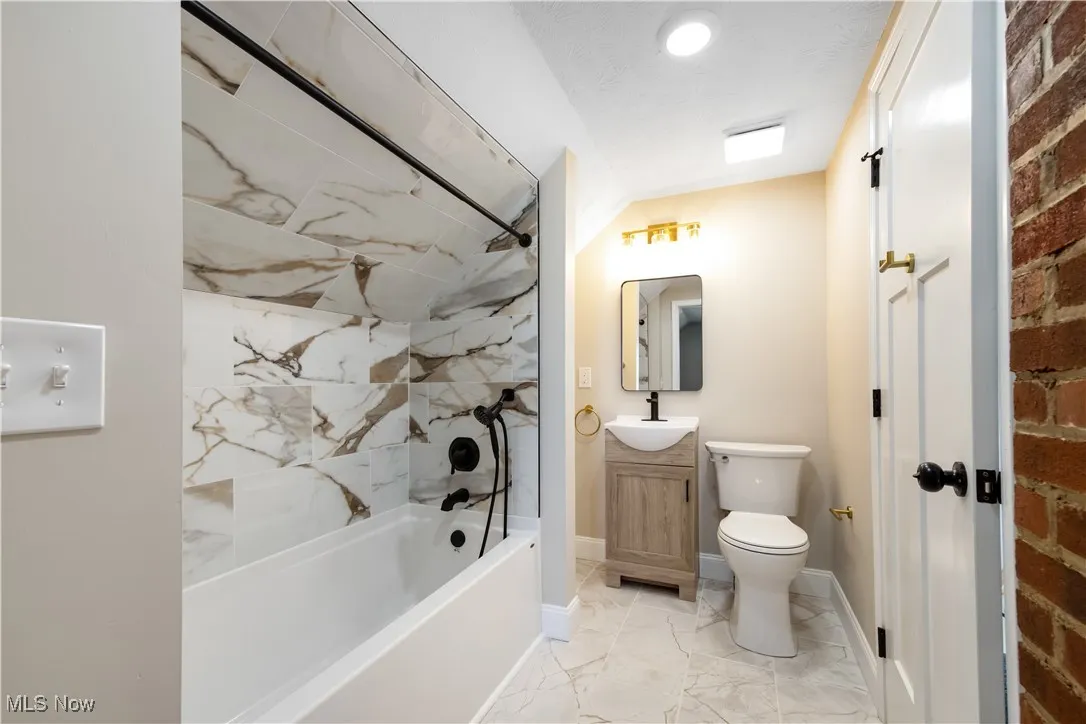 Full bath featuring bathing tub / shower combination, vanity, and light marble finish floors