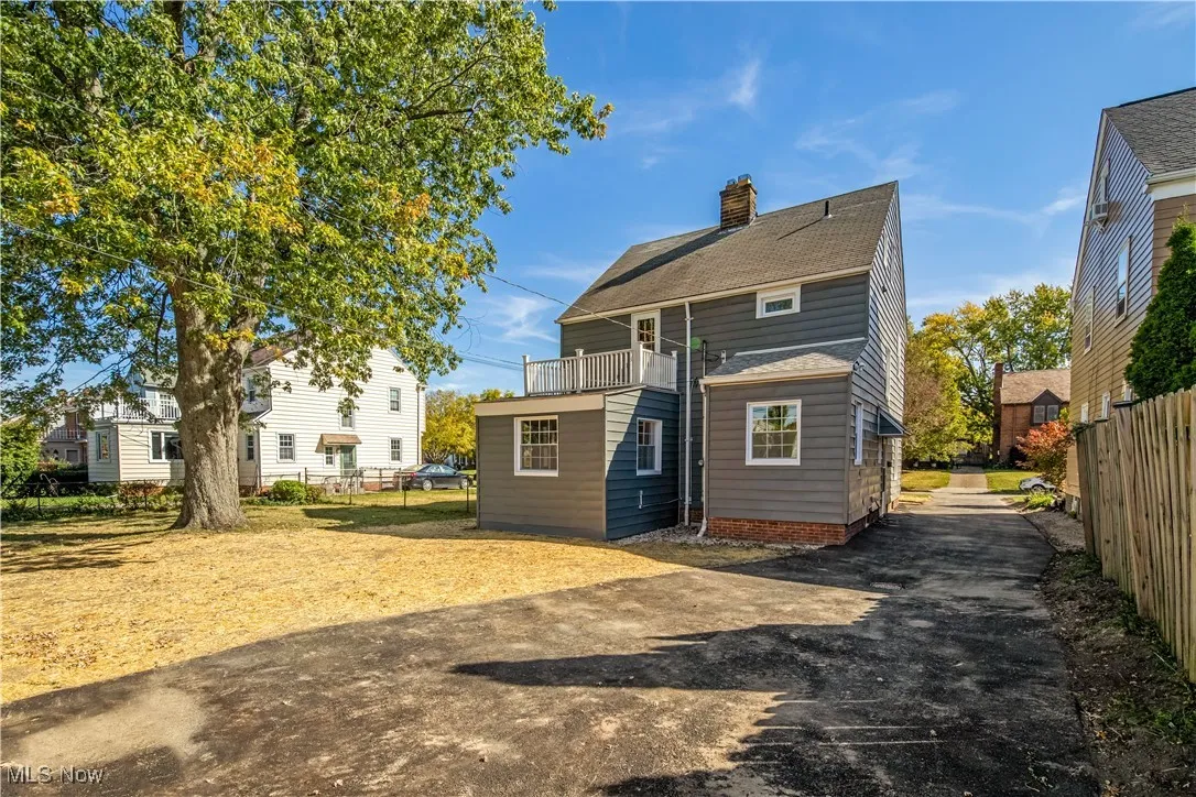 Back of house featuring a balcony, a chimney, and roof with shingles