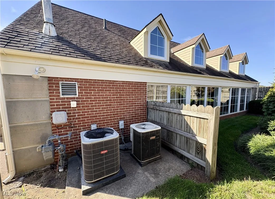 Exterior view of brick siding, a shingled roof, and a downspout