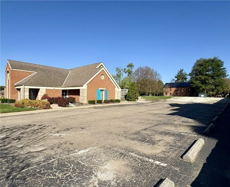 View of front of building with brick siding and uncovered parking