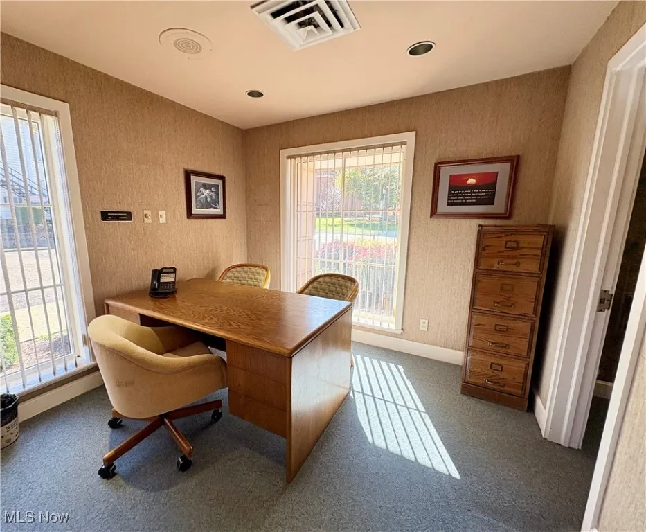 Carpeted office space featuring wallpapered walls