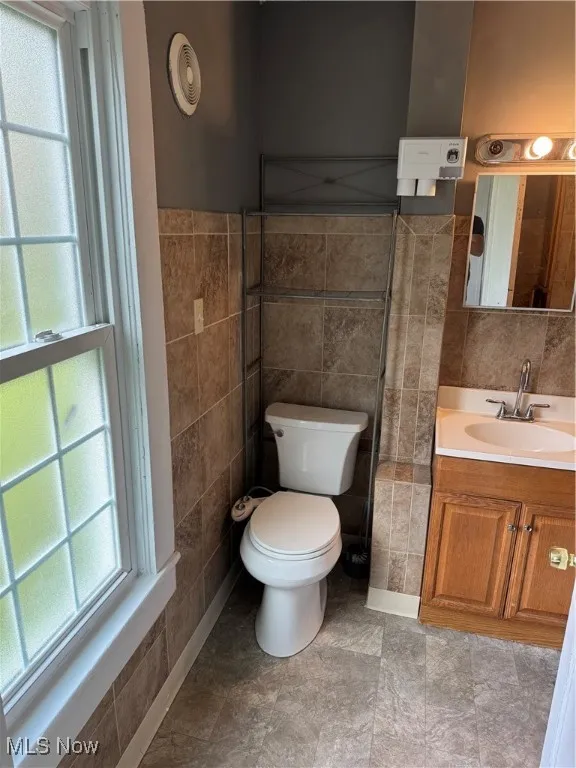 Half bath featuring vanity and tile walls