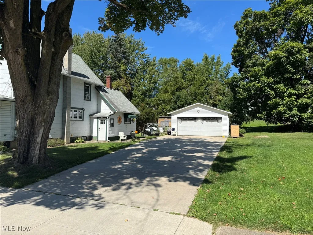View of property exterior with an outdoor structure, a yard, a garage, and a chimney