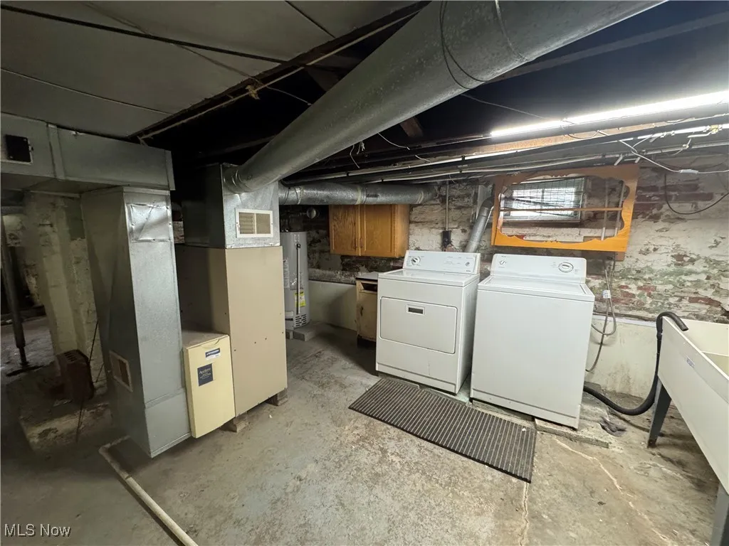 Unfinished basement featuring independent washer and dryer, heating unit, and gas water heater
