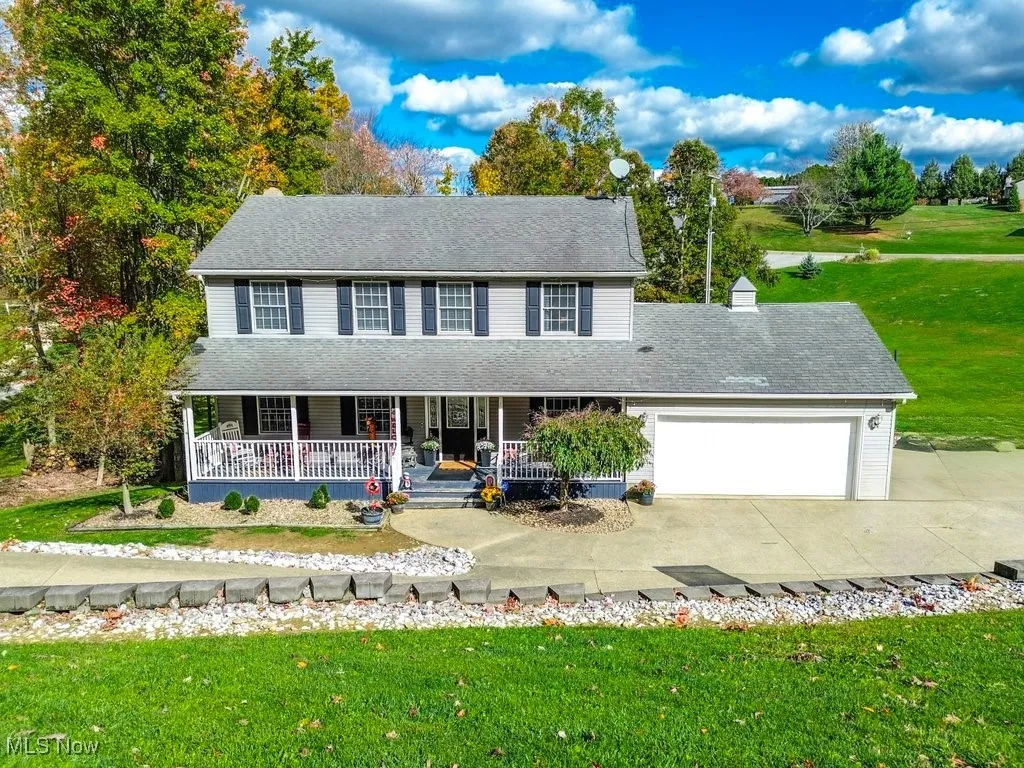 View of front of property featuring a porch, a front yard, an attached garage, concrete driveway, and a chimney