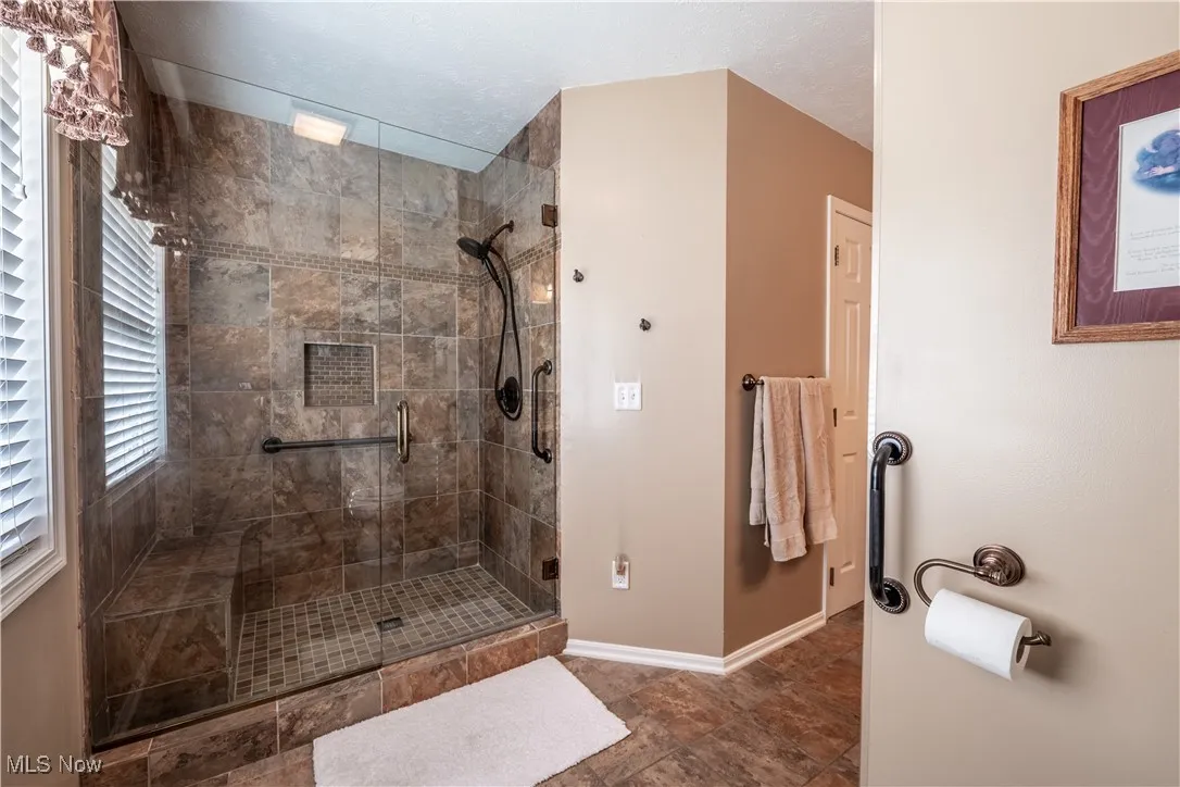 Beautiful step in tiled shower with glass doors and grab bars in Master Bath