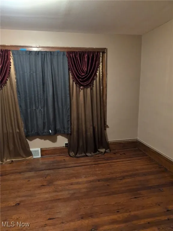 Empty room with dark wood-style floors and baseboards