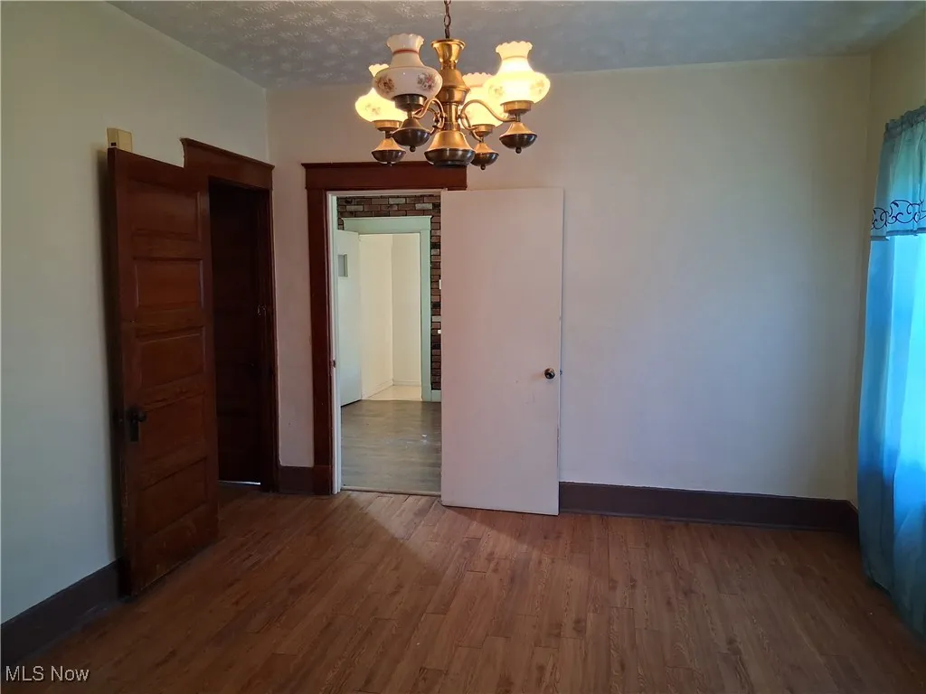 Unfurnished room featuring dark wood-style flooring, a chandelier, and a textured ceiling