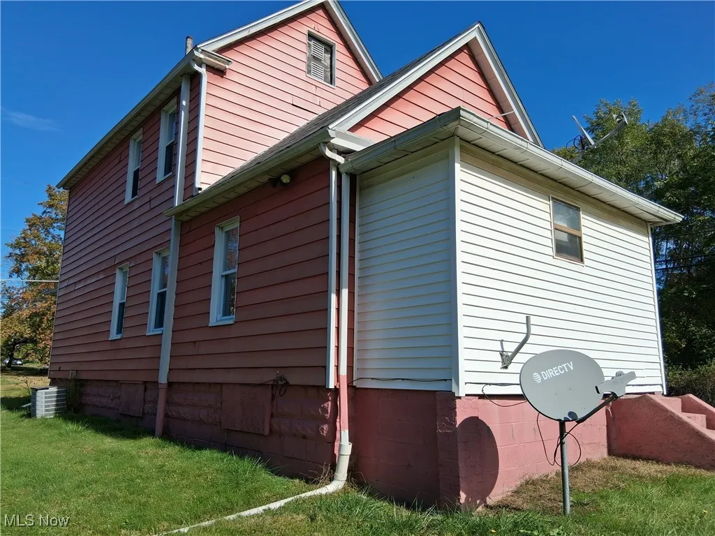 View of side of home featuring a yard and a central AC unit