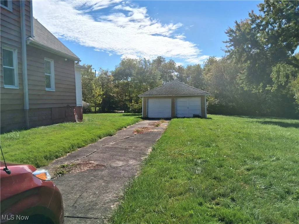 View of green lawn featuring an outdoor structure and a detached garage