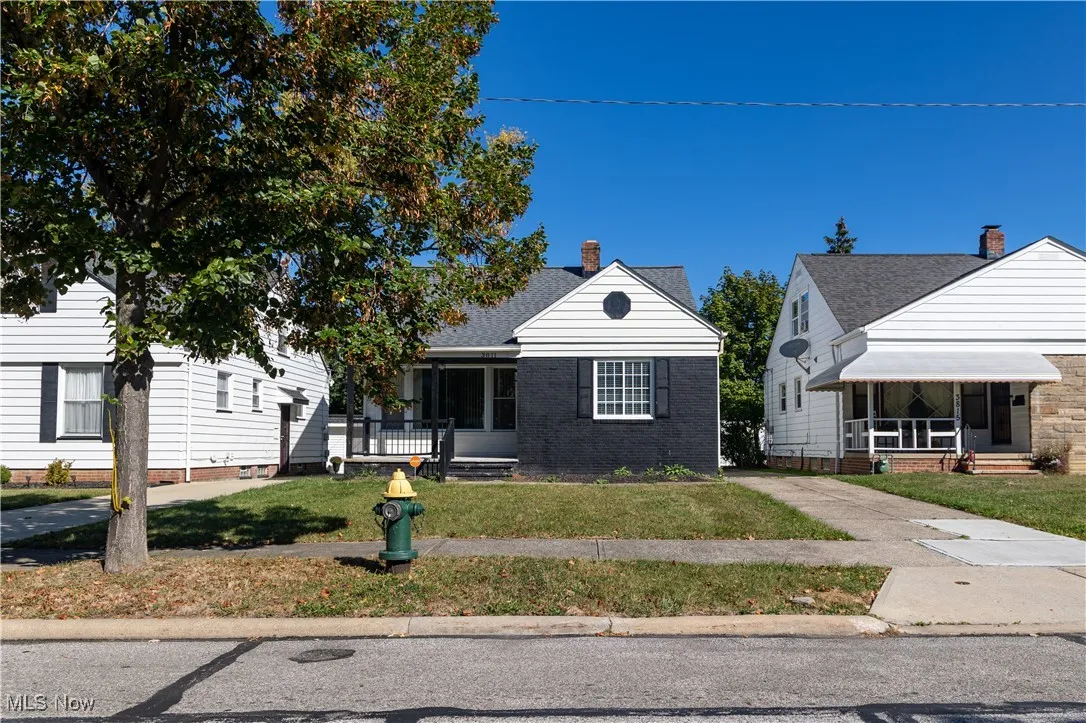 Bungalow-style home featuring a front lawn, covered porch, a chimney, and brick siding