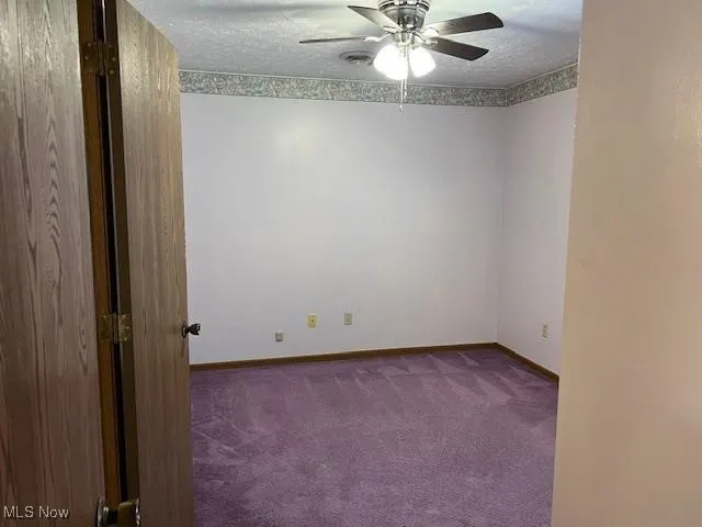 Jack and Jill bedroom with dark colored carpet, ceiling fan, and a textured ceiling. This room also has mirrored sliders closet doors.