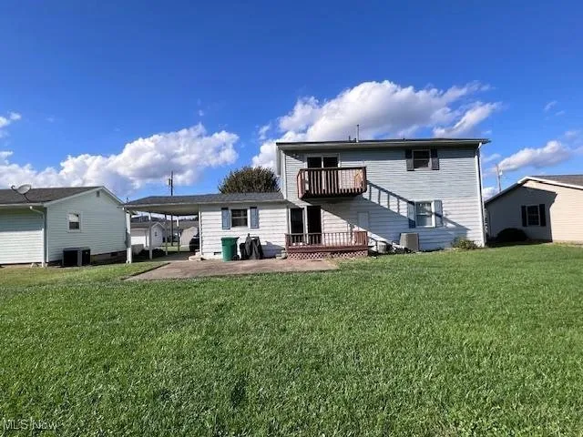 Rear view of house featuring a lawn, a deck, a carport, and a patio area. The lawn is nice and plush!