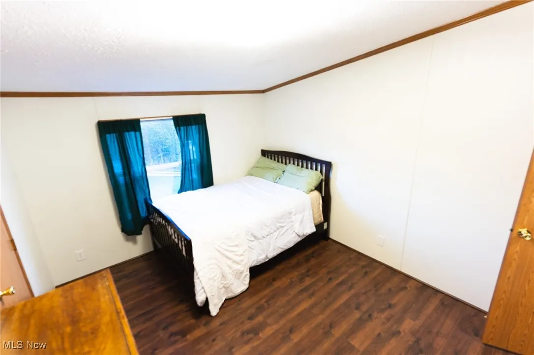 Bedroom featuring ornamental molding and wood finished floors