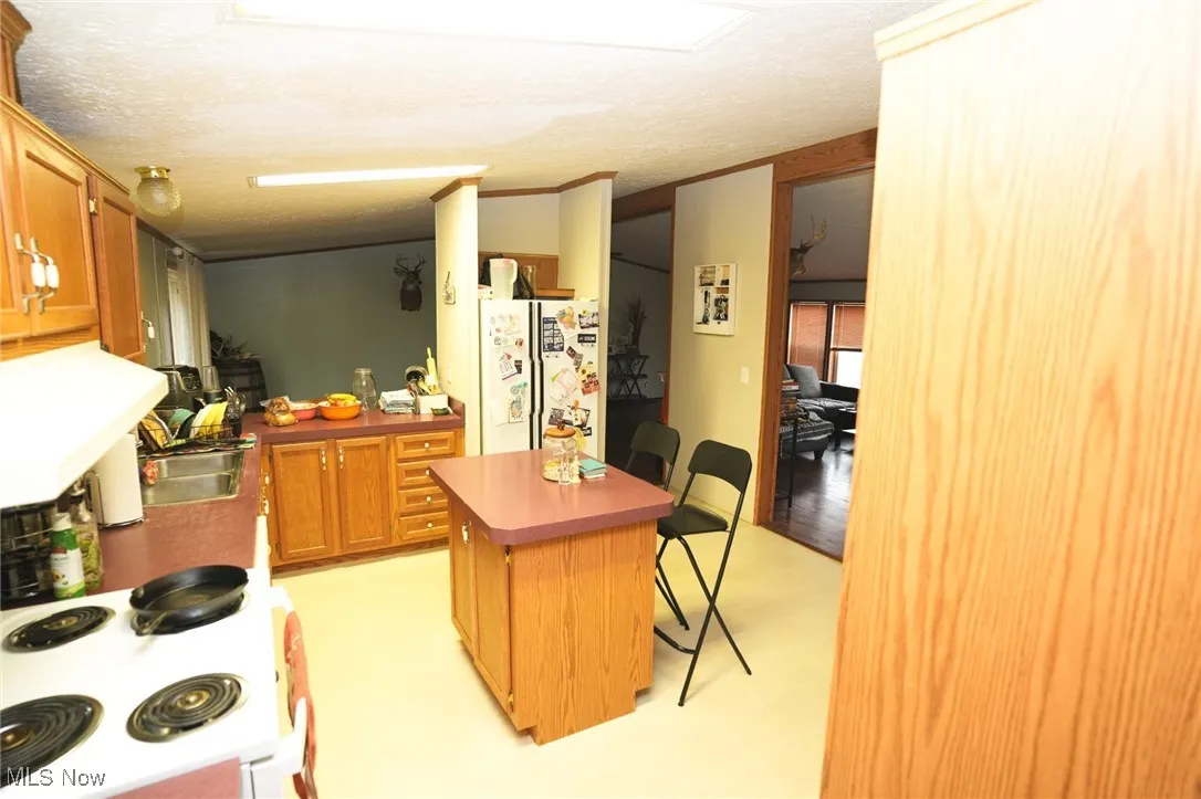 Kitchen with a kitchen island, white appliances, a kitchen breakfast bar, brown cabinets, and extractor fan
