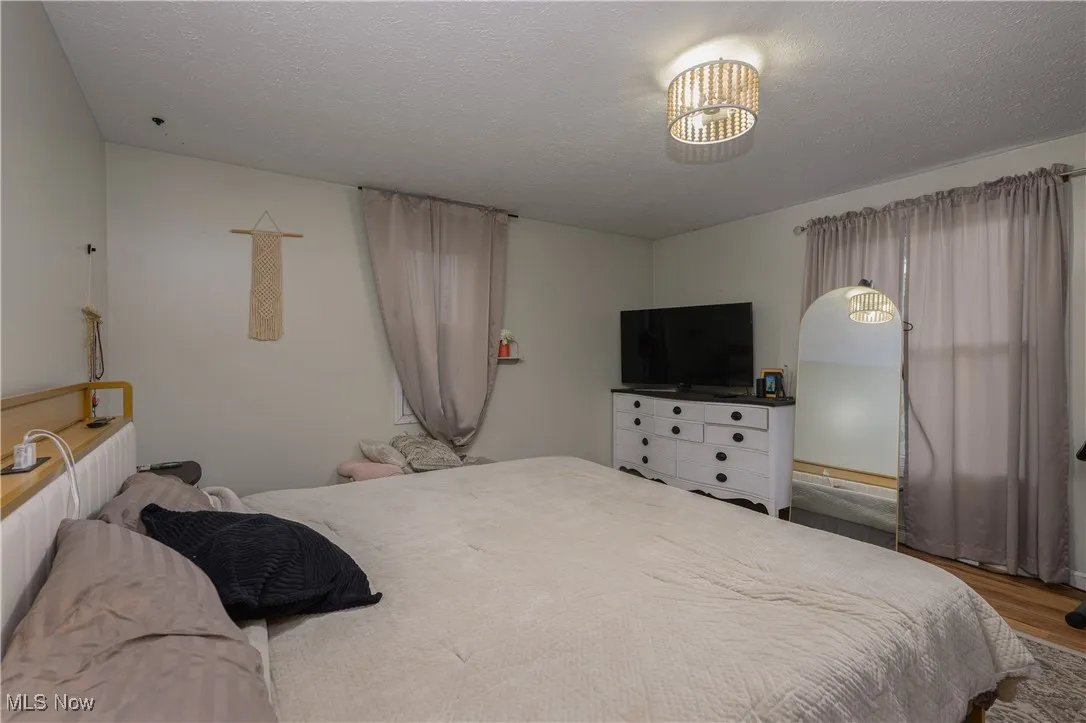 Bedroom with a textured ceiling and wood finished floors