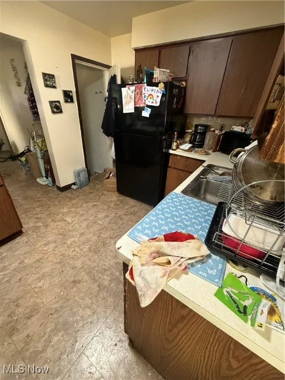 Kitchen featuring light countertops, refrigerator, and dark brown cabinets