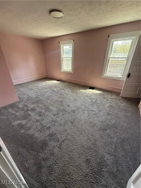 Empty room with a textured ceiling and carpet flooring