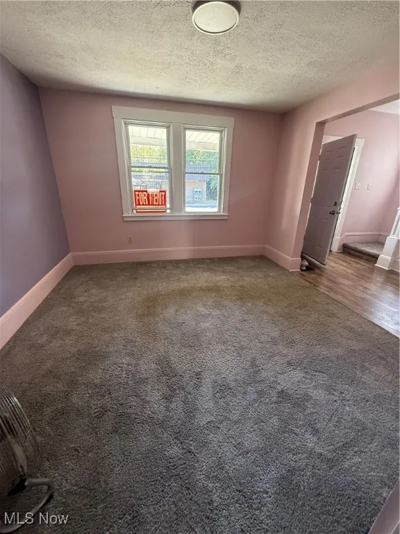 Spare room with dark colored carpet and a textured ceiling