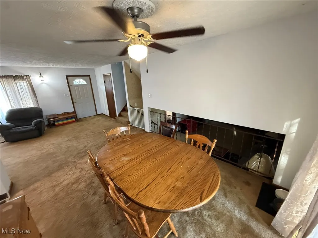 Dining space with carpet floors, a textured ceiling, and a ceiling fan