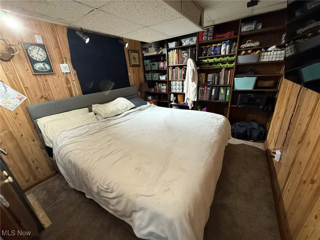 Bedroom with wood walls, a paneled ceiling, and carpet flooring