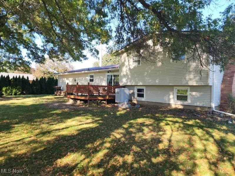 Rear view of property featuring a deck and a lawn