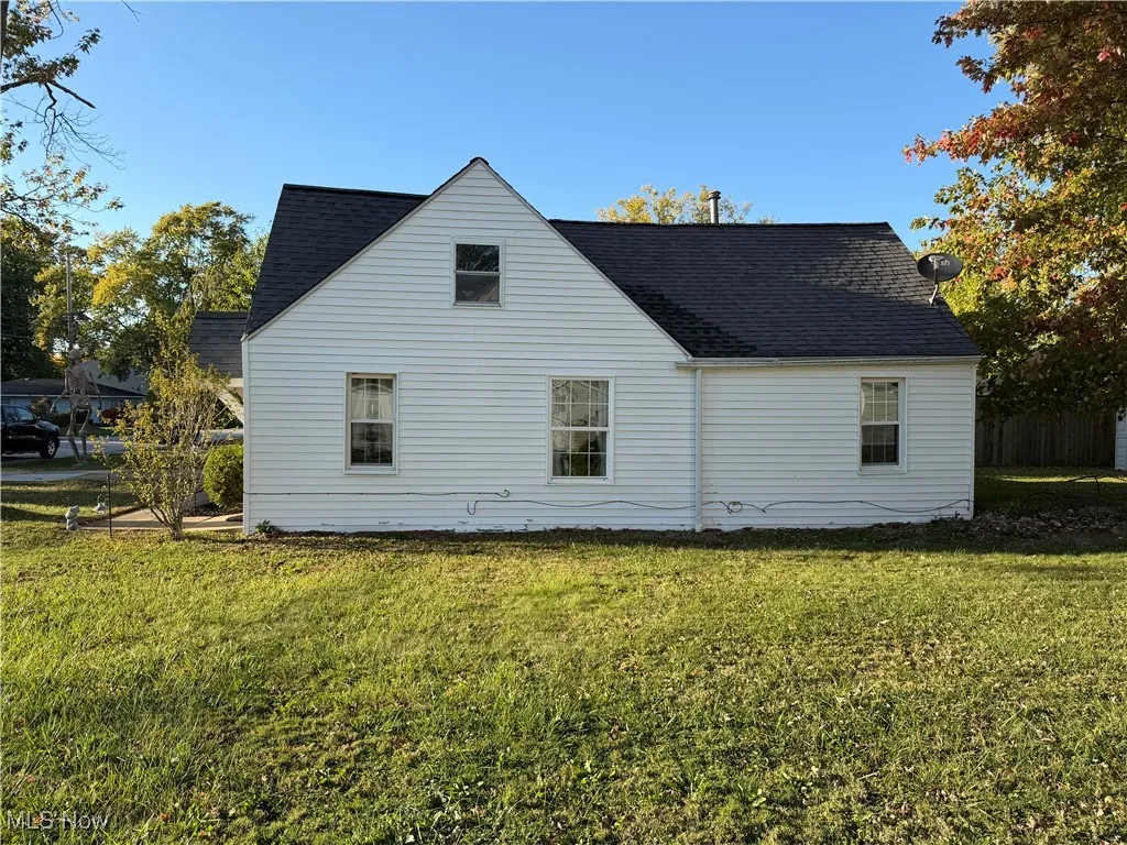 View of side of home featuring a yard and roof with shingles