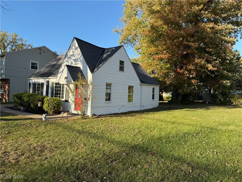 View of front of home with a front yard and roof with shingles