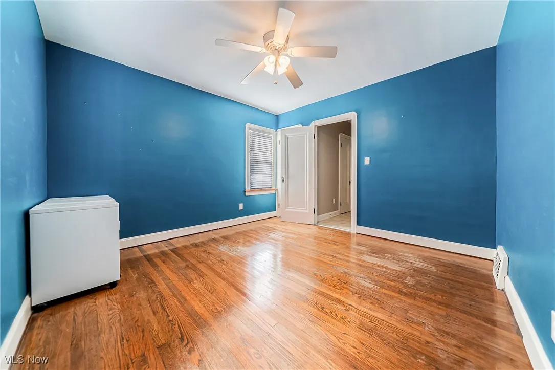 Unfurnished room with wood finished floors, a ceiling fan, and a baseboard heating unit