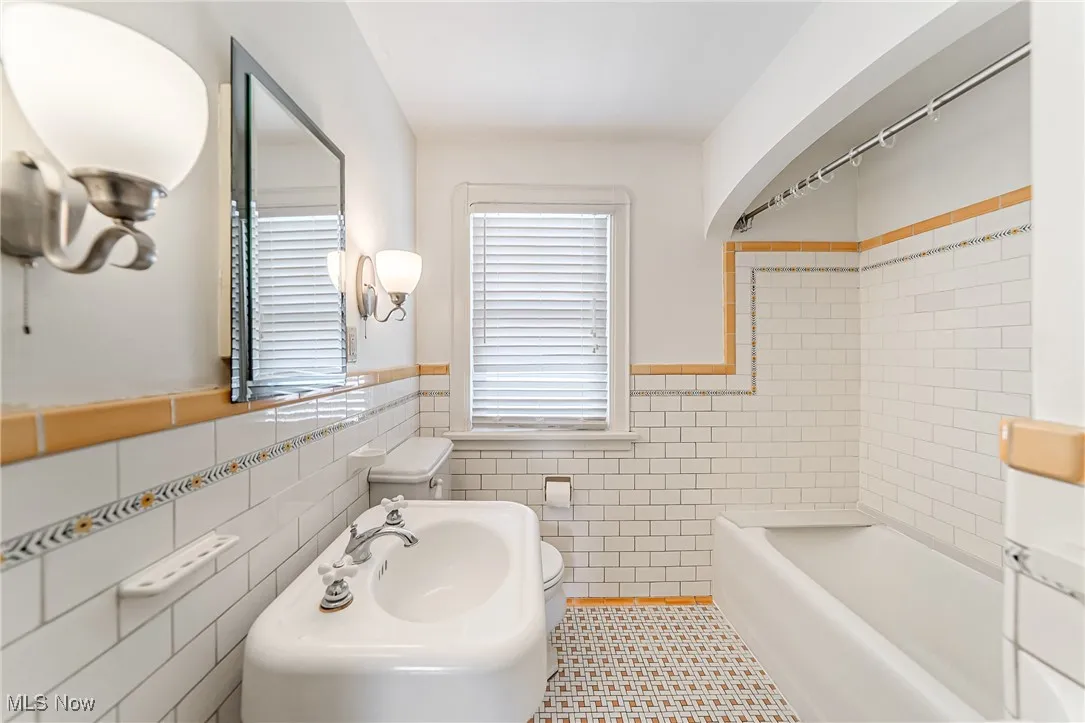 Bathroom with tile walls, a wainscoted wall, tub / shower combination, and tile patterned floors