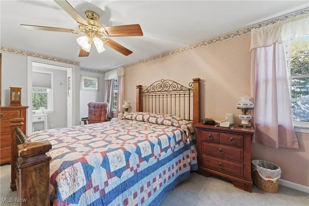Bedroom featuring light carpet, wallpapered walls, and a ceiling fan