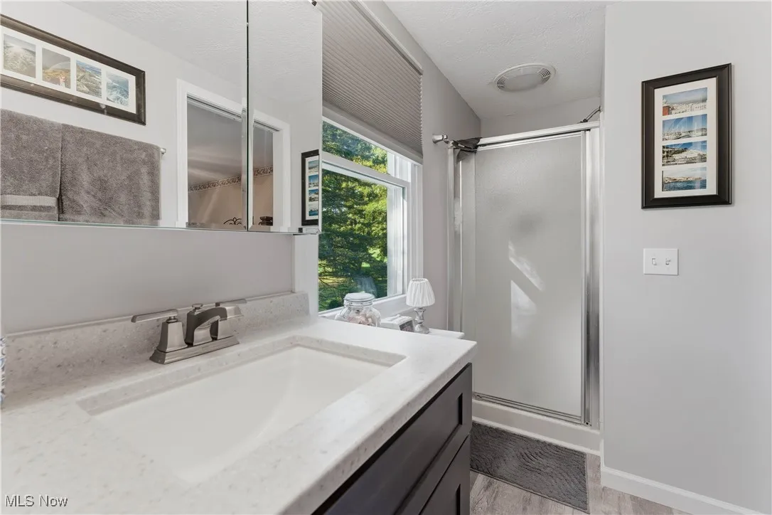 Bathroom featuring vanity, a shower stall, a textured ceiling, and light wood-style flooring