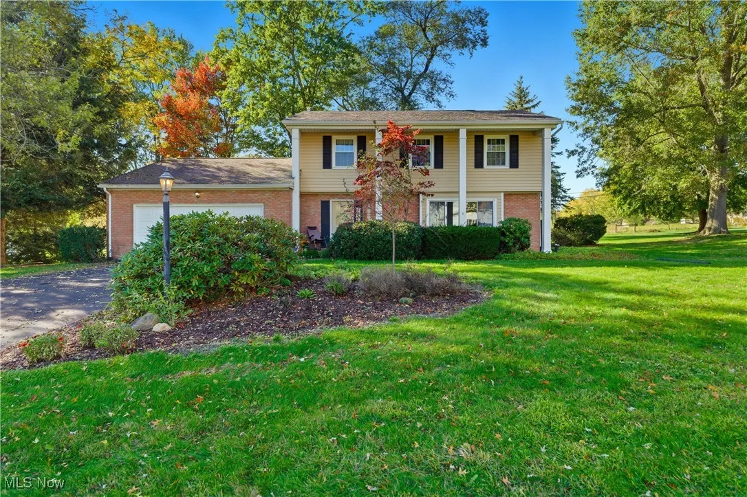 View of front of home with a front yard, an attached garage, brick siding, and concrete driveway