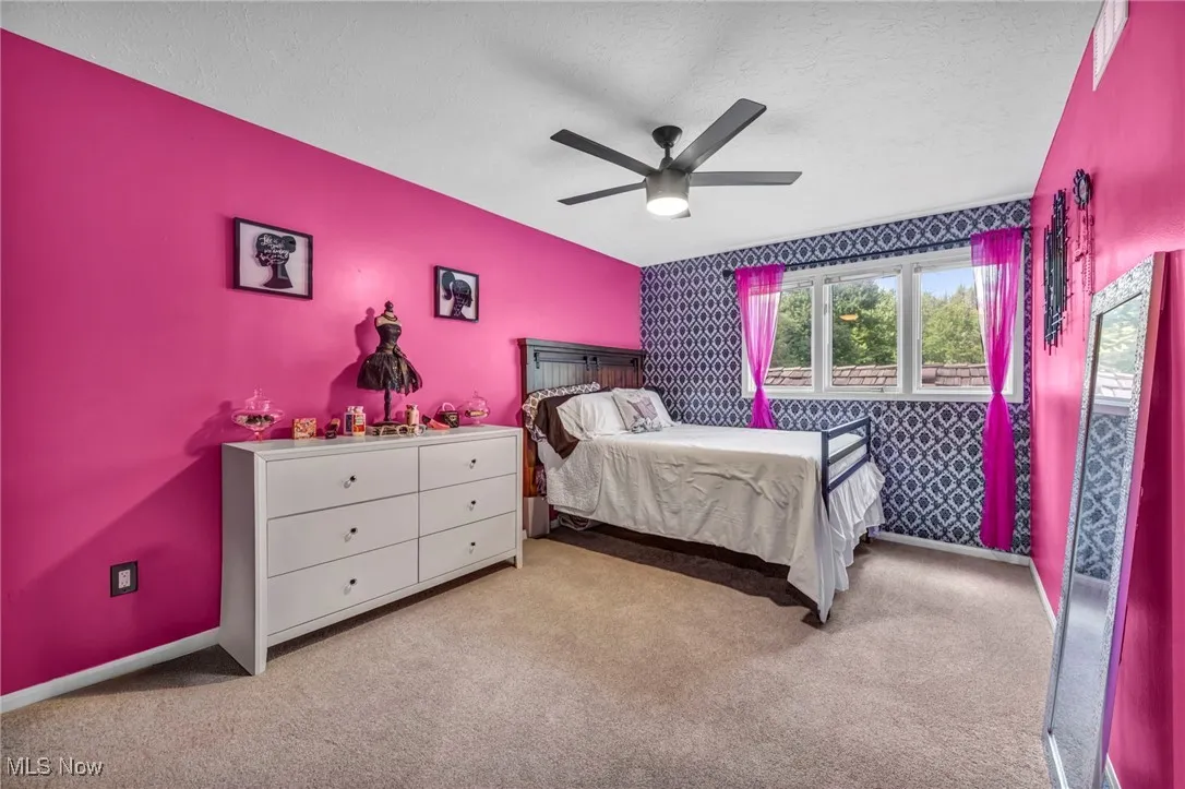 Bedroom with carpet, wallpapered walls, a textured ceiling, a ceiling fan, and an accent wall