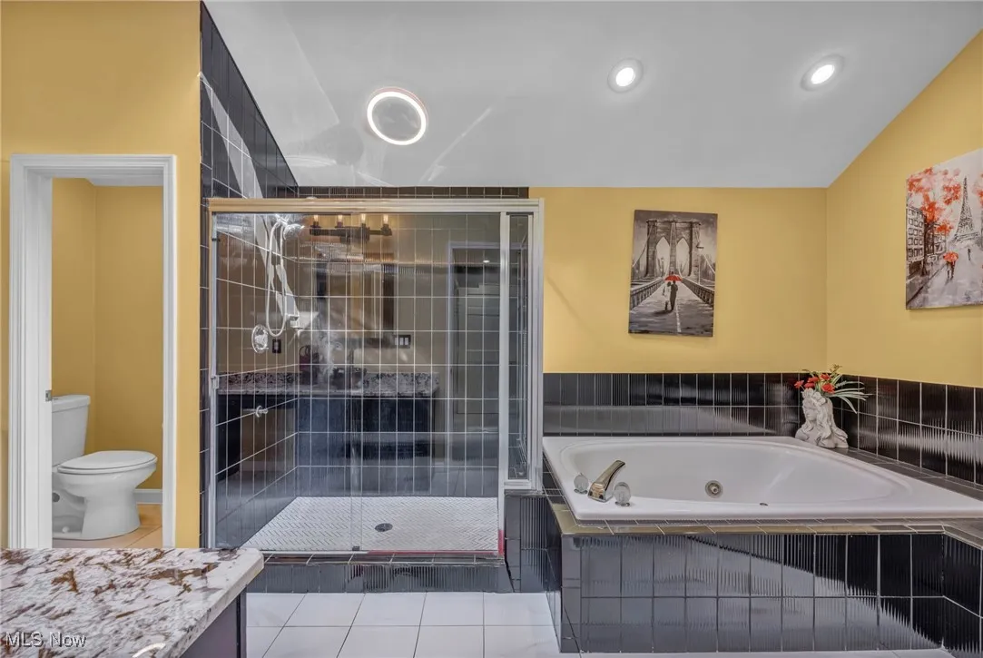 Bathroom with a stall shower, a tub with jets, vanity, tile patterned floors, and recessed lighting
