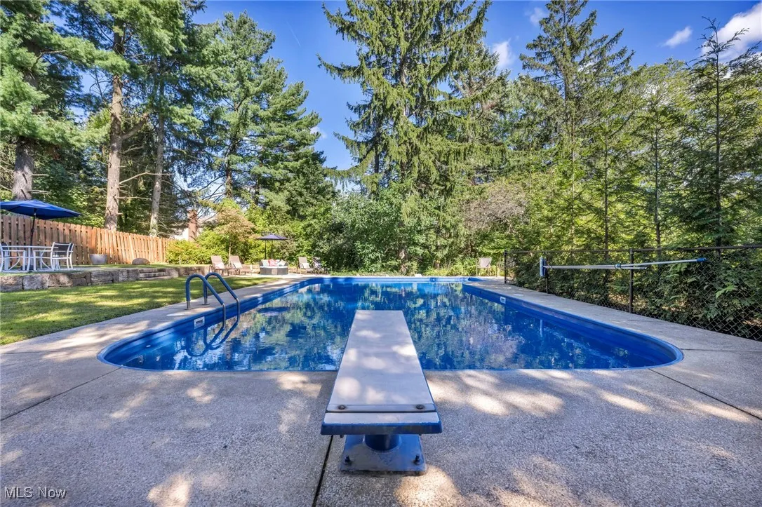 View of swimming pool with a diving board and a patio
