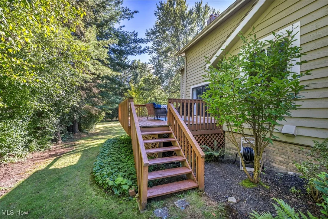 View of green lawn featuring a deck and stairs