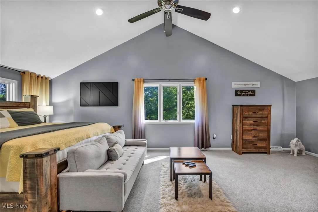 Carpeted bedroom with beam ceiling, a ceiling fan, and high vaulted ceiling