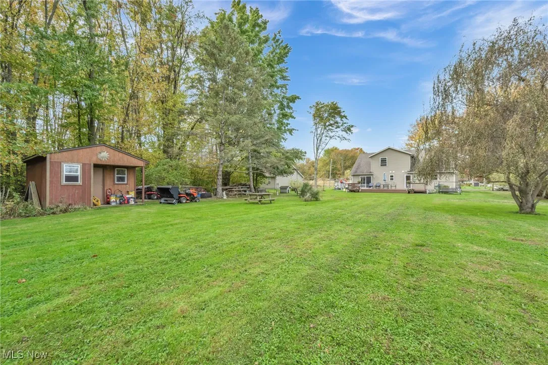 View of grassy yard with an outbuilding and view of scattered trees