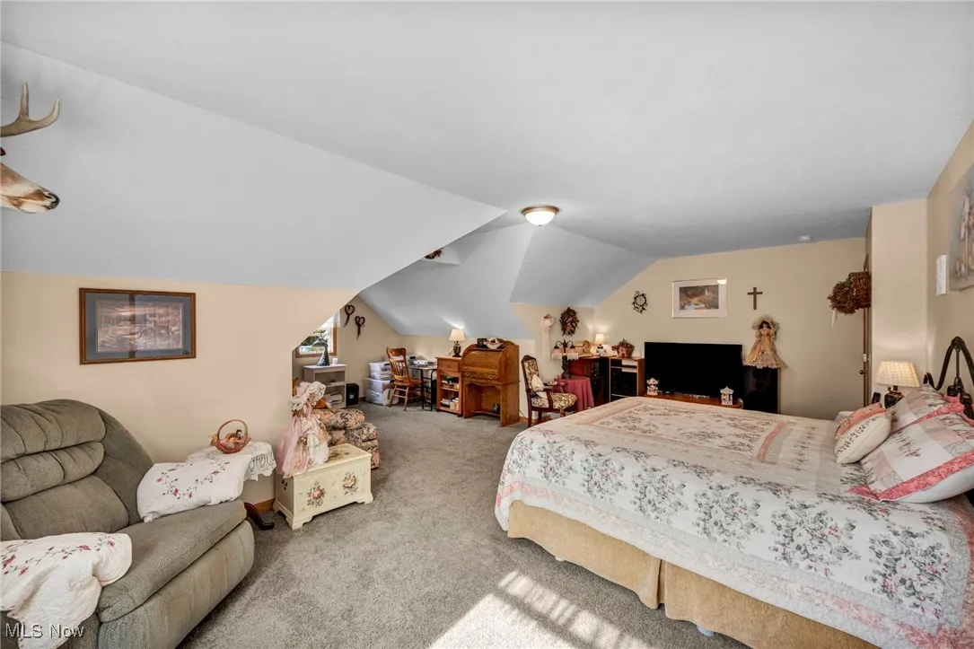 Carpeted bedroom featuring lofted ceiling and an office area