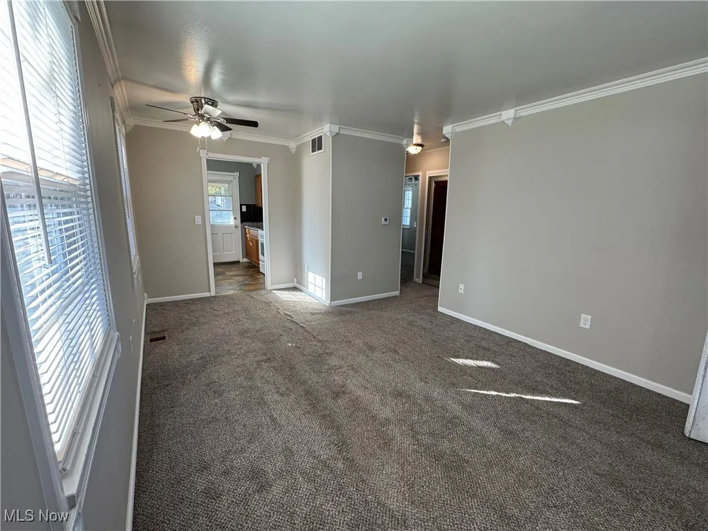 Carpeted living room with crown molding and an AC wall unit