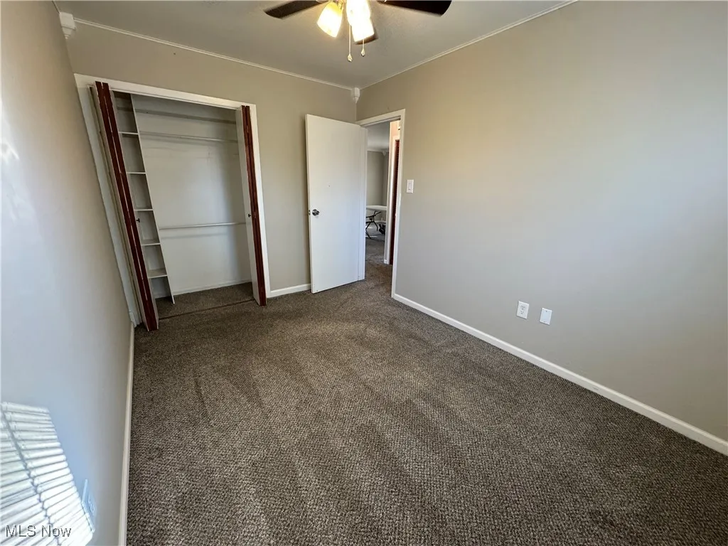Unfurnished bedroom featuring carpet, a closet, ceiling fan, and ornamental molding