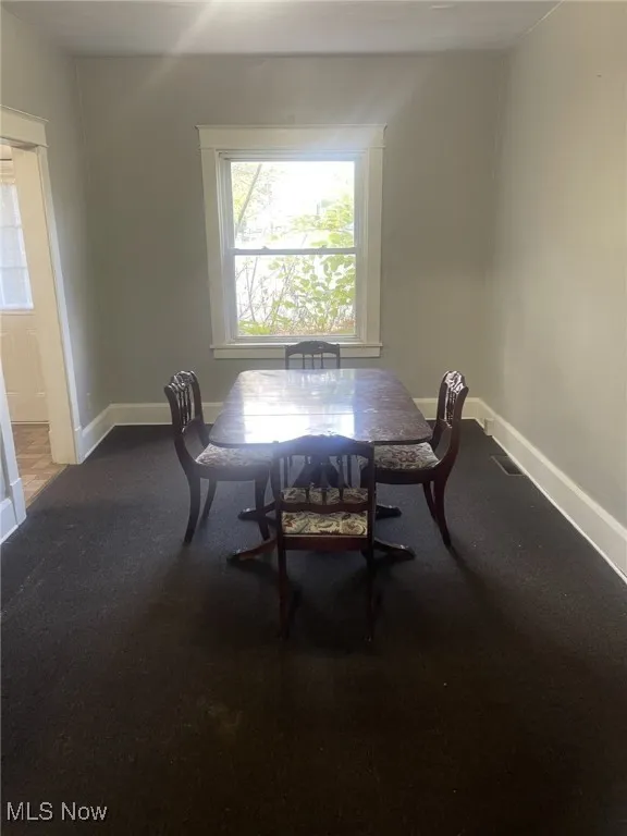 Dining area with baseboards and dark colored carpet