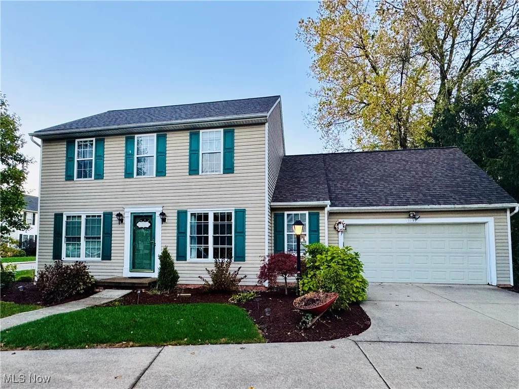 Colonial house with an attached garage, concrete driveway, and roof with shingles