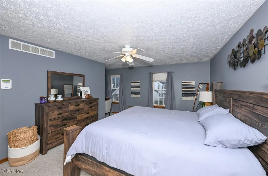 Bedroom featuring a textured ceiling, carpet floors, and a ceiling fan