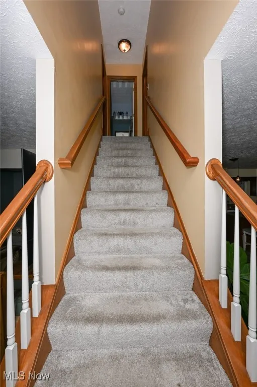 Stairway featuring a textured ceiling