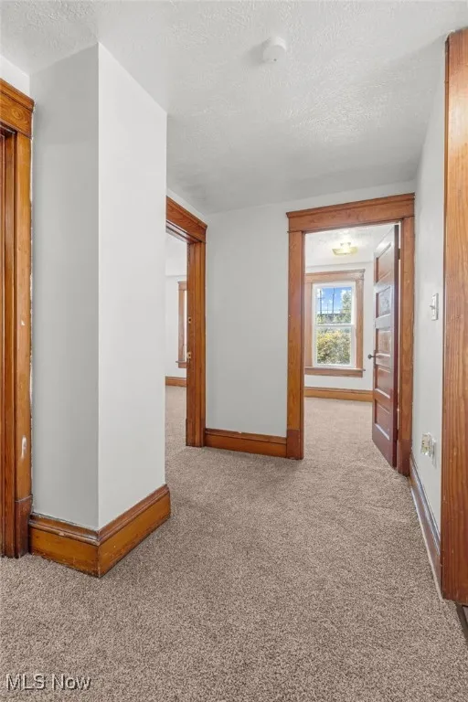 Hall with carpet floors and a textured ceiling