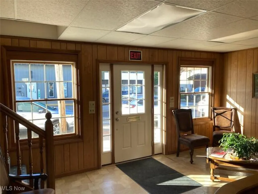Doorway to outside featuring wooden walls, stairs, and tile patterned floors