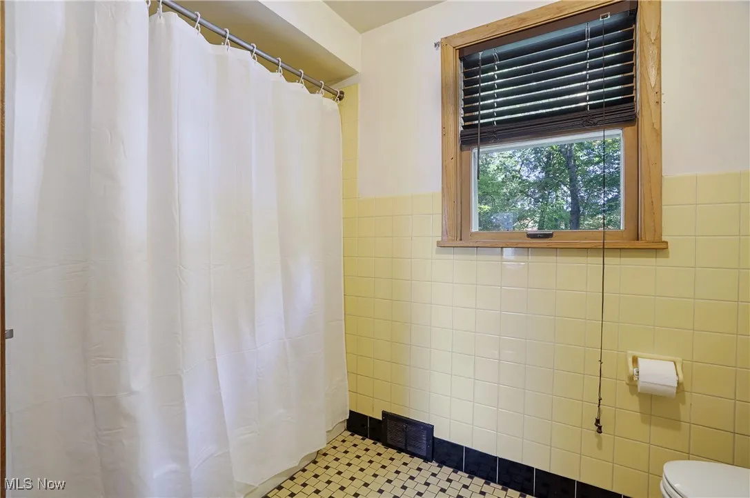 Full bathroom with a stall shower, tile walls, and tile patterned floors