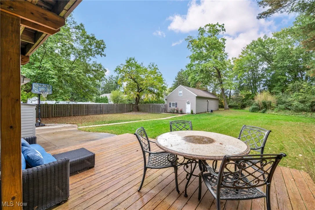 Wooden deck with outdoor dining area and side patio and wooded area